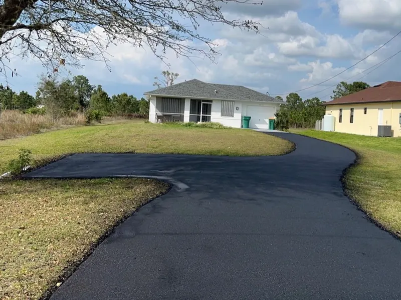 Freshly paved curving asphalt driveway at a Florida home